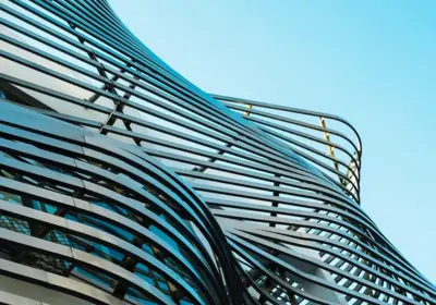 The sweeping curved glass facade of a contemporary congress centre against a blue sky