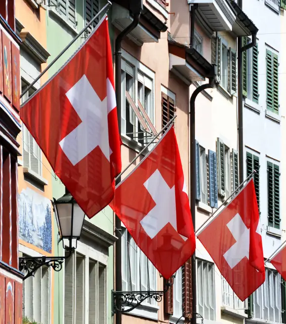 Swiss flags hanging off old buildings in Zurich Switzerland