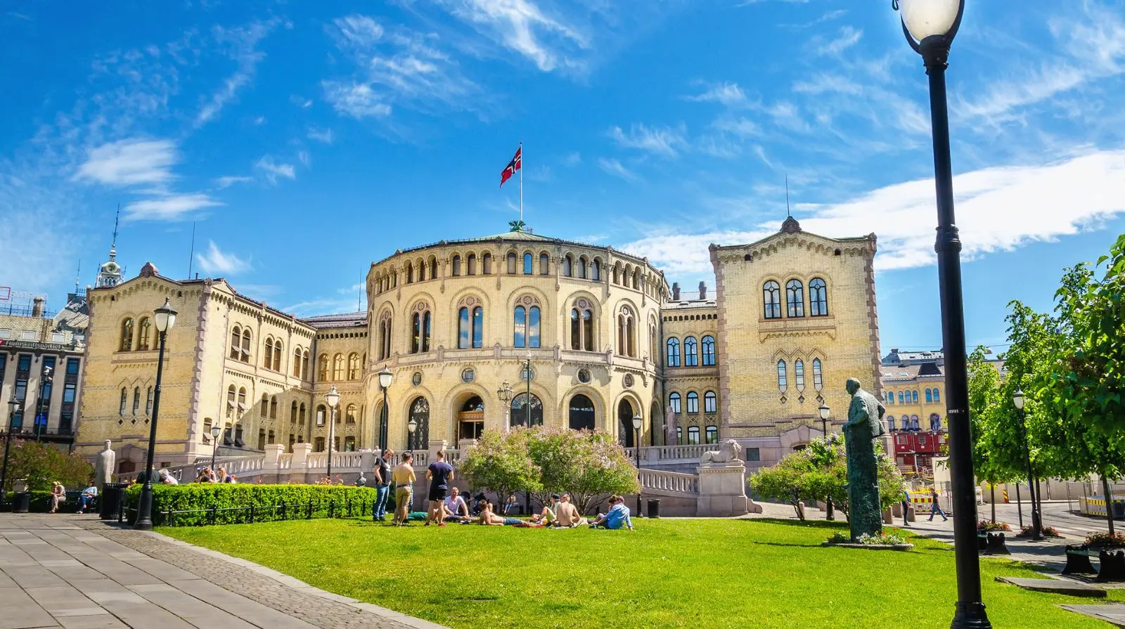 Norwegian Parliament building in Oslo with people relaxing on the lawn, highlighting the city’s accessible green spaces and civic architecture.