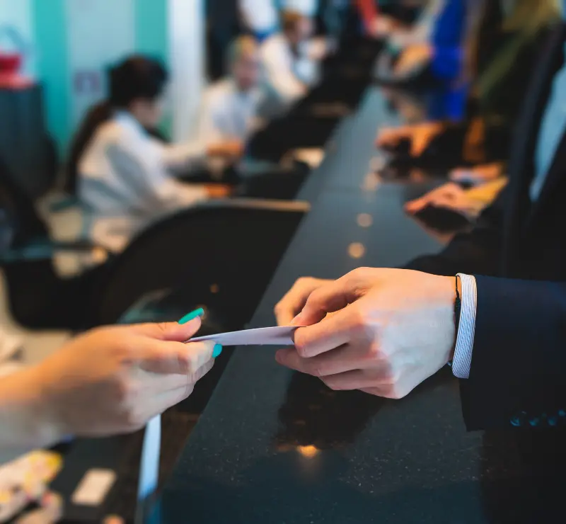 Person being handed a card checking into accommodation or event at desk