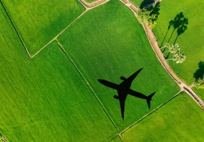Airplane flying over green landscape representing carbon tracking for travel