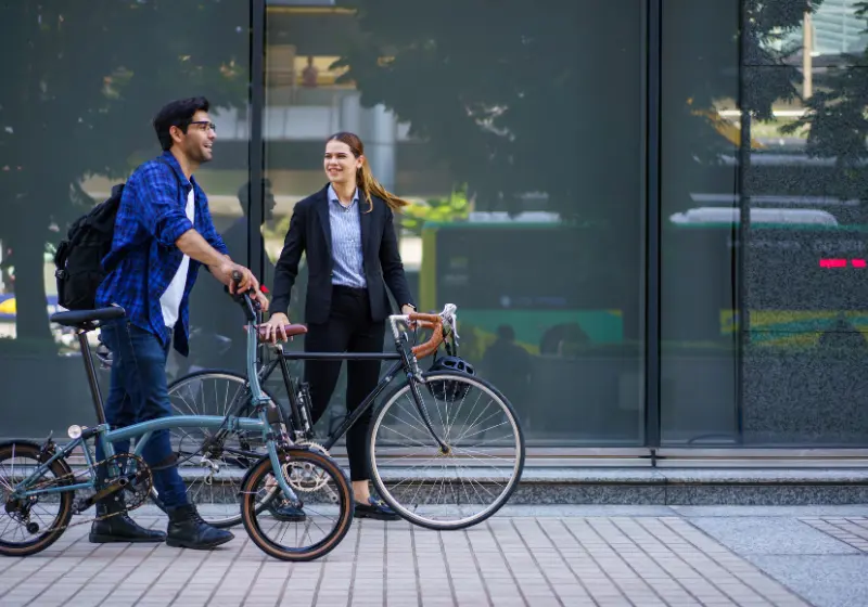 Two professionals with bicycles outside an office building representing sustainable transport