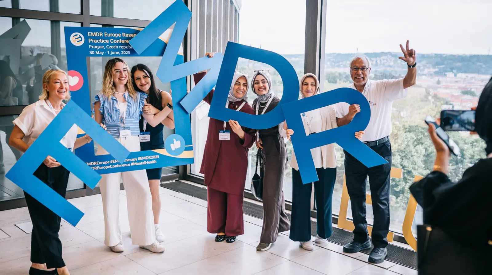 Group photo of congress delegates with EMDR letter props at the EMDR Europe Research & Practice Conference 2025 in Prague