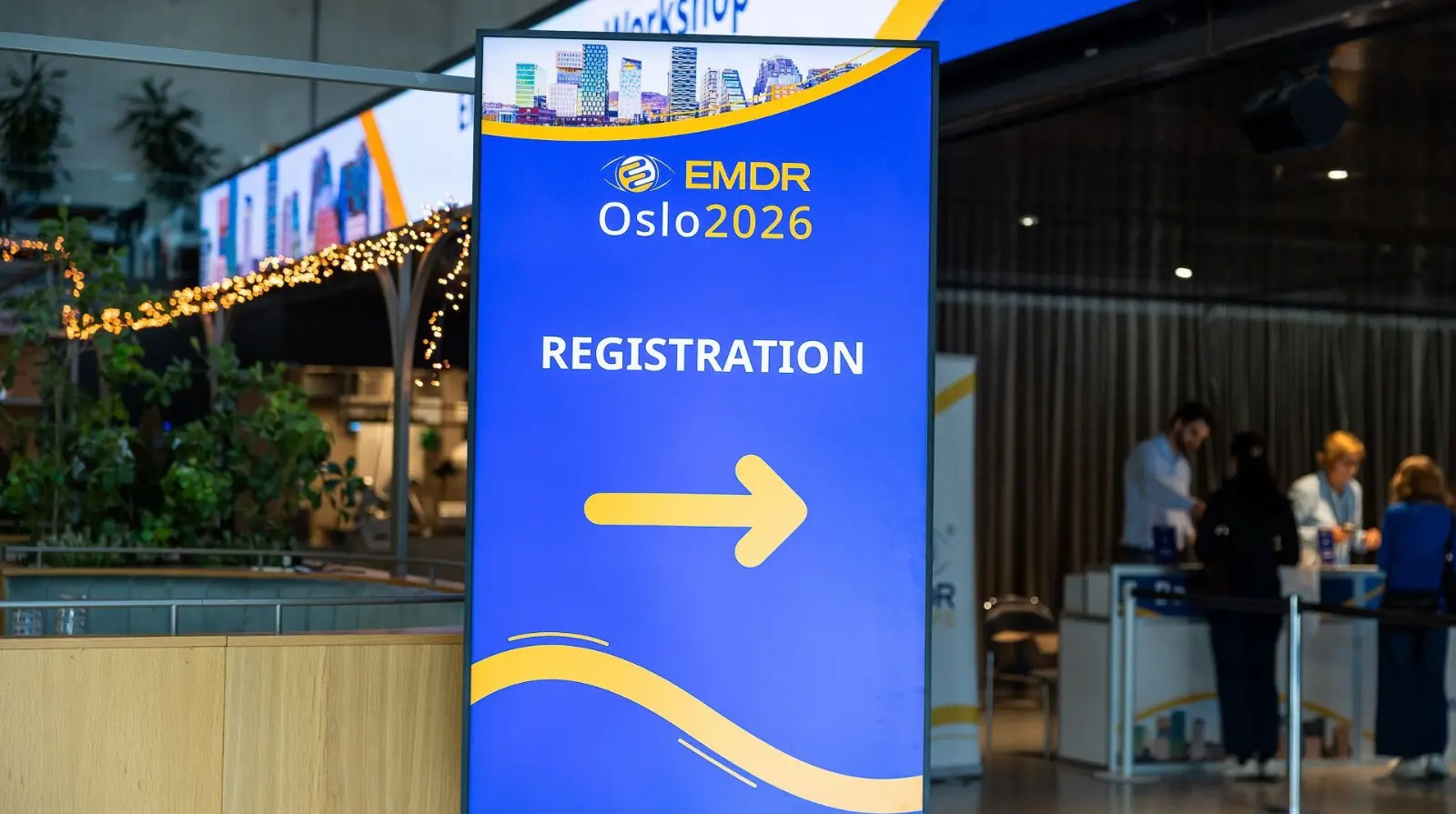 A blue EMDR Oslo 2026 sign reading REGISTRATION with a yellow arrow and a registration desk beyond.