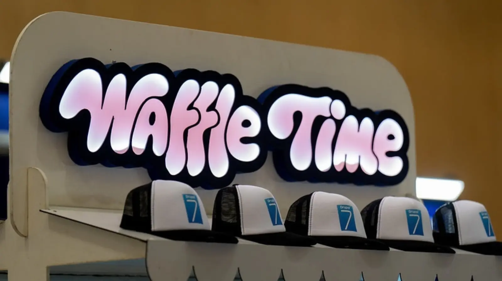 An illuminated Waffle Time sign above a congress refreshment stand.