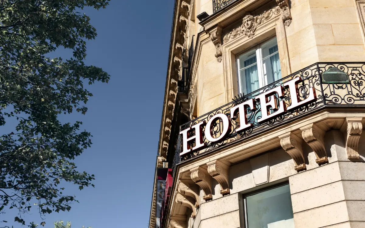 Hotel facade with signage, sky, and tree branches