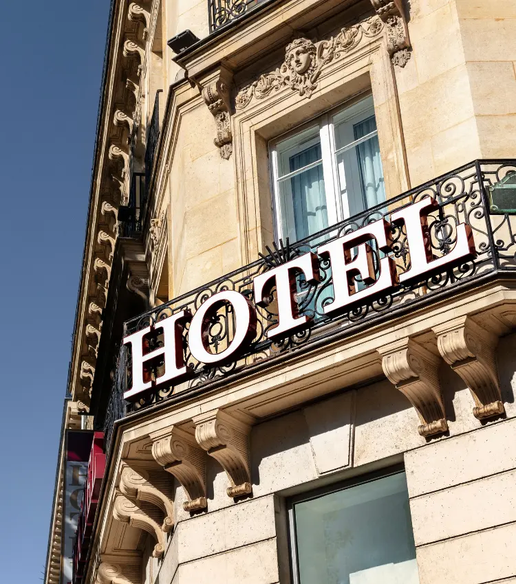 Hotel facade with signage, sky, and tree branches