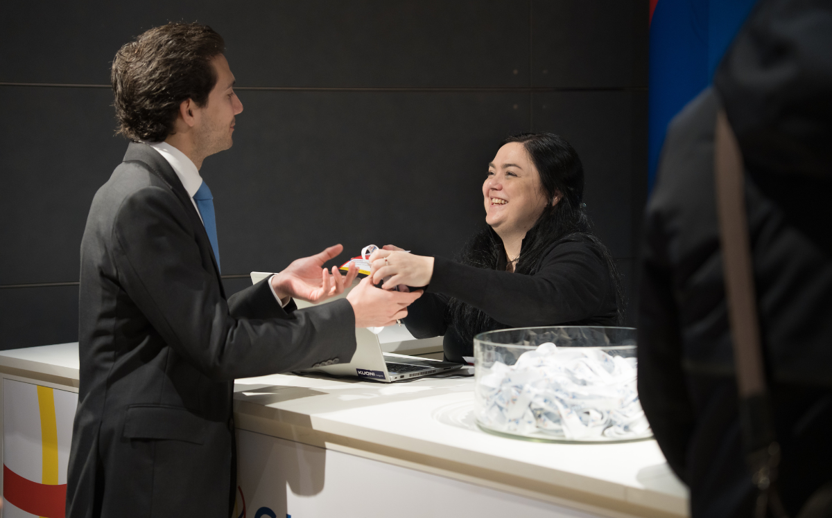 Kuoni Tumlare Congress staff member handing a delegate their welcome pack at a congress event