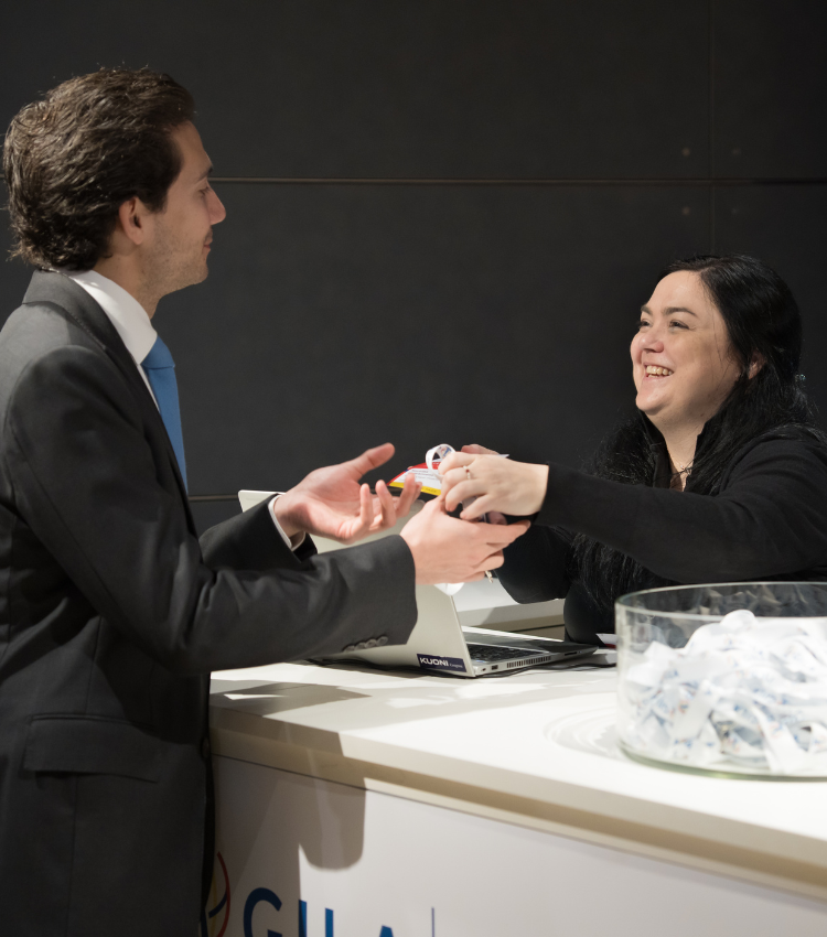 Kuoni Tumlare Congress staff member handing a delegate their welcome pack at a congress event