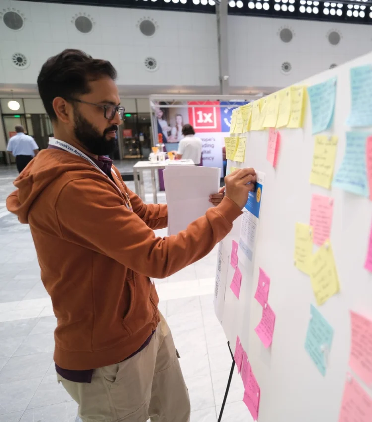 An organiser maps out a congress plan on a sticky-note board at an event venue.