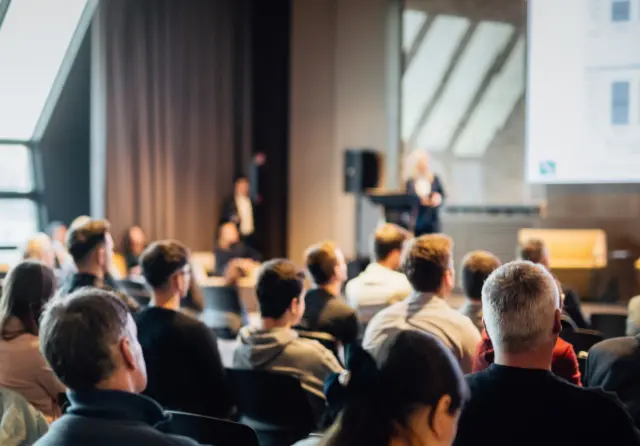 People sat in an auditorium listening to a speaker at a congress