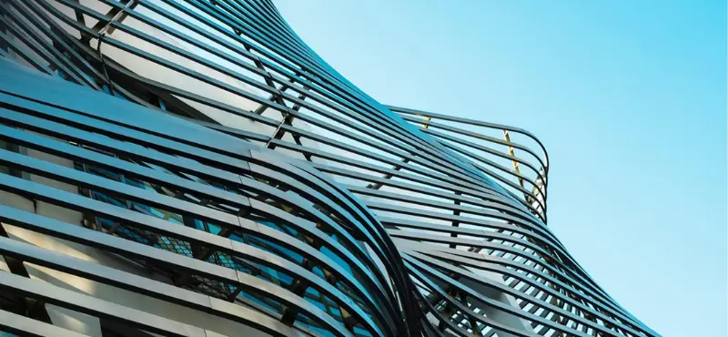 The sweeping curved glass facade of a contemporary congress centre against a blue sky