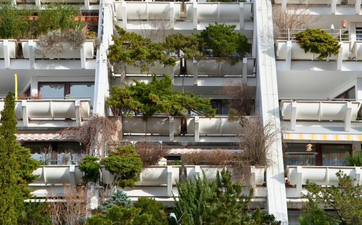 Modern residential building in Vienna featuring tiered balconies filled with plants and greenery, showcasing sustainable urban architecture and integrated vertical gardens.